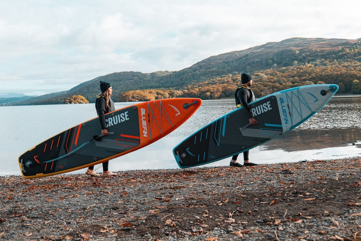 two people holding paddleboards at the edge of the lake