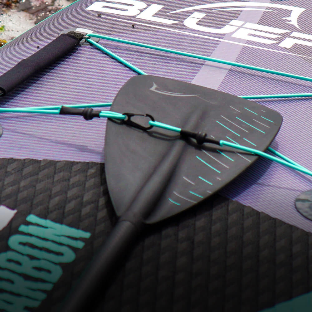 Close-up of a paddleboard featuring a black fin, turquoise bungee cords, and textured surface.