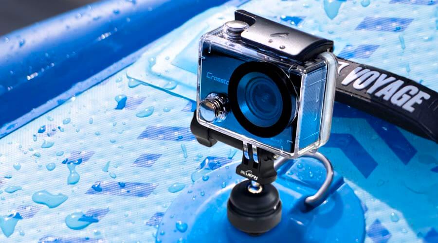 Waterproof action camera mounted on a blue paddleboard with droplets of water on the surface