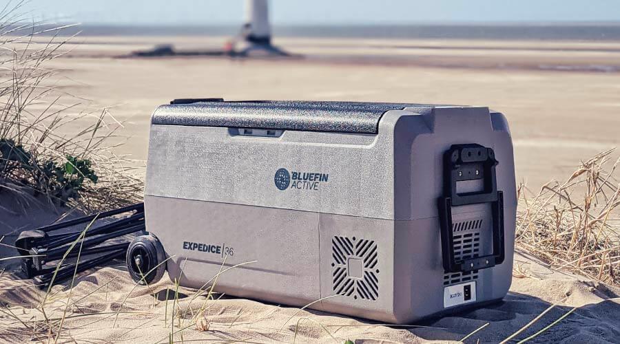 Bluefin Active cooler on sandy beach, with wheels and handle for easy transport, in natural setting.