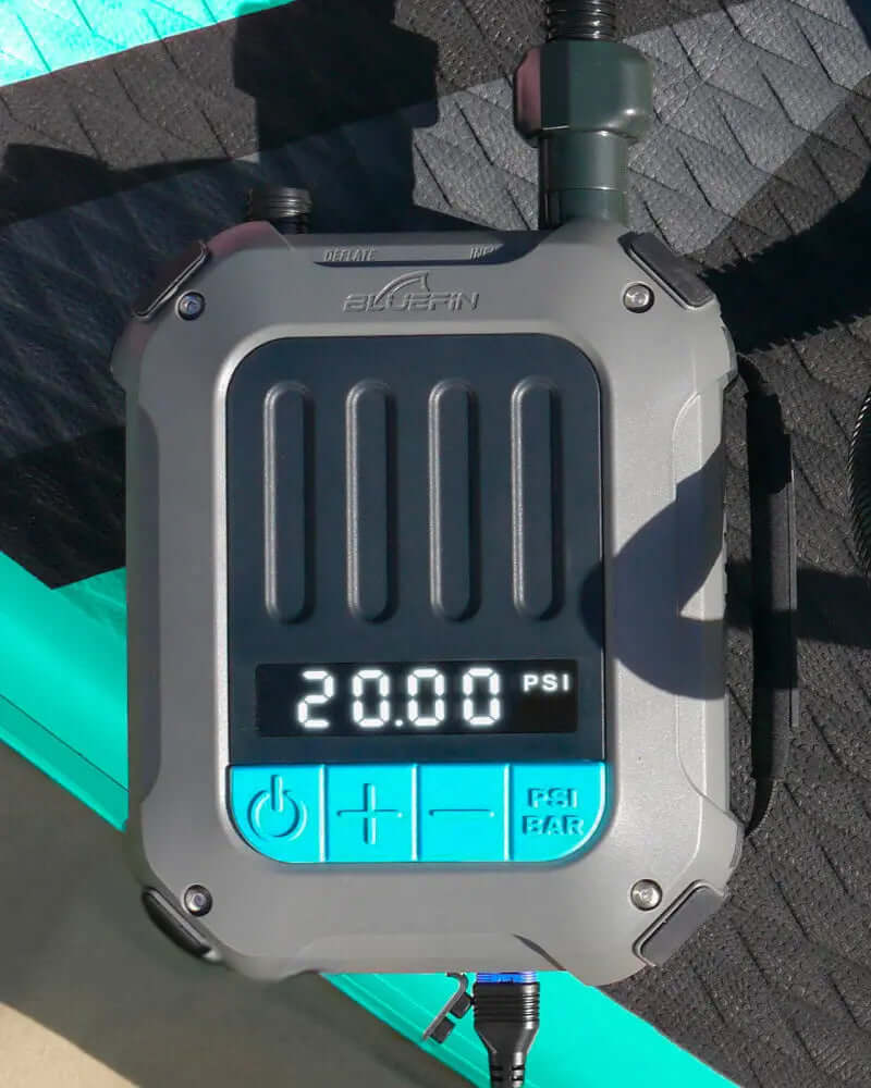 Digital pressure gauge showing 20.00 PSI, part of a Bluefin SUP inflation system on a textured surface.