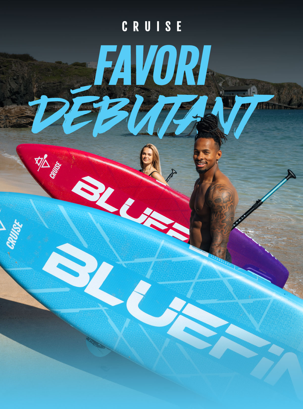 Two paddleboarders on a beach, one with a blue board and the other with a red board, smiling.