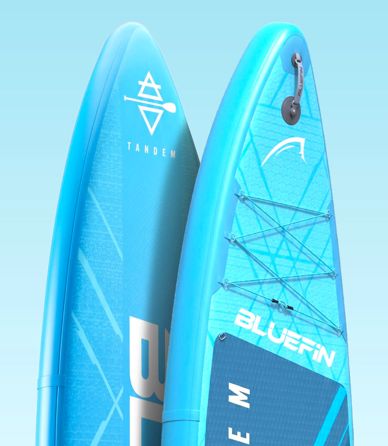 Two blue inflatable paddleboards with logos, one labeled TANDEM and the other BLUEFIN