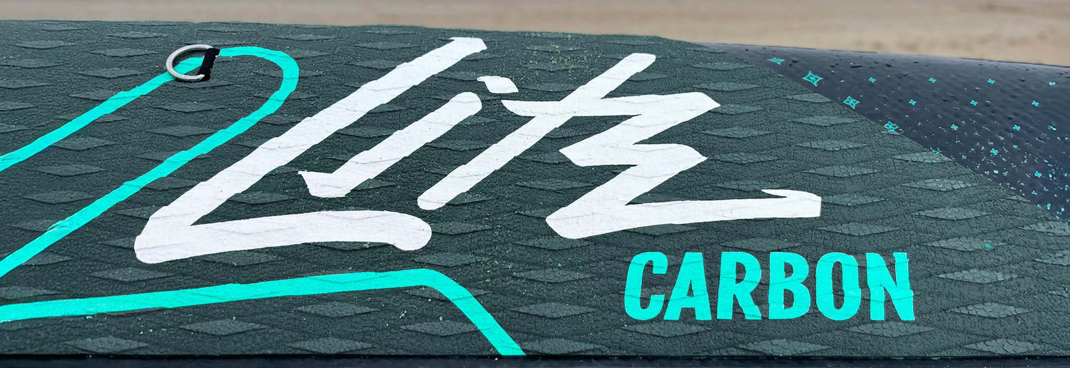 Textured paddleboard deck with white "Litz" logo and "CARBON" in turquoise lettering